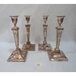 A set of four Adam style plated candlesticks, repousse decorated, with square tapered stems and