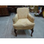 An 18th century upholstered armchair on shell moulded walnut cabriole legs. (All legs with lower