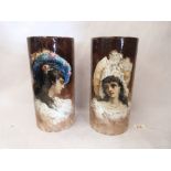 A pair of of cylindrical pottery glazed vases, each painted with an elegant lady and signed 'CLAIR'.