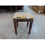 A Victorian walnut stool with distressed tapestry seat, on turned legs