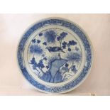 A chinese blue and white charger, painted with a bird in prunus within a band of reserved flowers