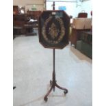 A 19th century mahogany polescreen with foliate needlework banner, on scrolled tripod support with