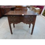 A George III oak lowboy with one long over two short drawers and a shaped apron, raised on chamfered