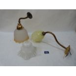 Period lighting. Two brass wall lamps, one with a Vaseline glass shade, the other a frosted amber