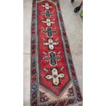 A red ground eastern carpet runner. 108' x 31'