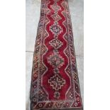 A red ground eastern carpet runner. 110' x 27'