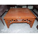 A Chinese lacquered low table with geometrically fret carved sides, on square legs. 38' wide