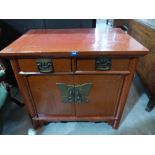 A Chinese lacquered cabinet enclosed by a pair of doors under a pair of frieze drawers, 31' wide