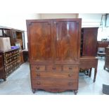 A George III mahogany linen press, the pair of flame veneered doors enclosing four sliding trays,