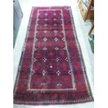 A red ground eastern rug. 108' x 49'. Areas of wear