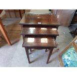 A nest of three mahogany occasional tables with inlet glass tops