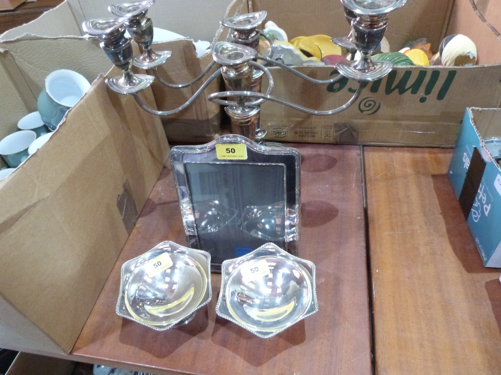 A pair of plated three light candelabra, a pair of plated bonbon dishes and a photograph frame