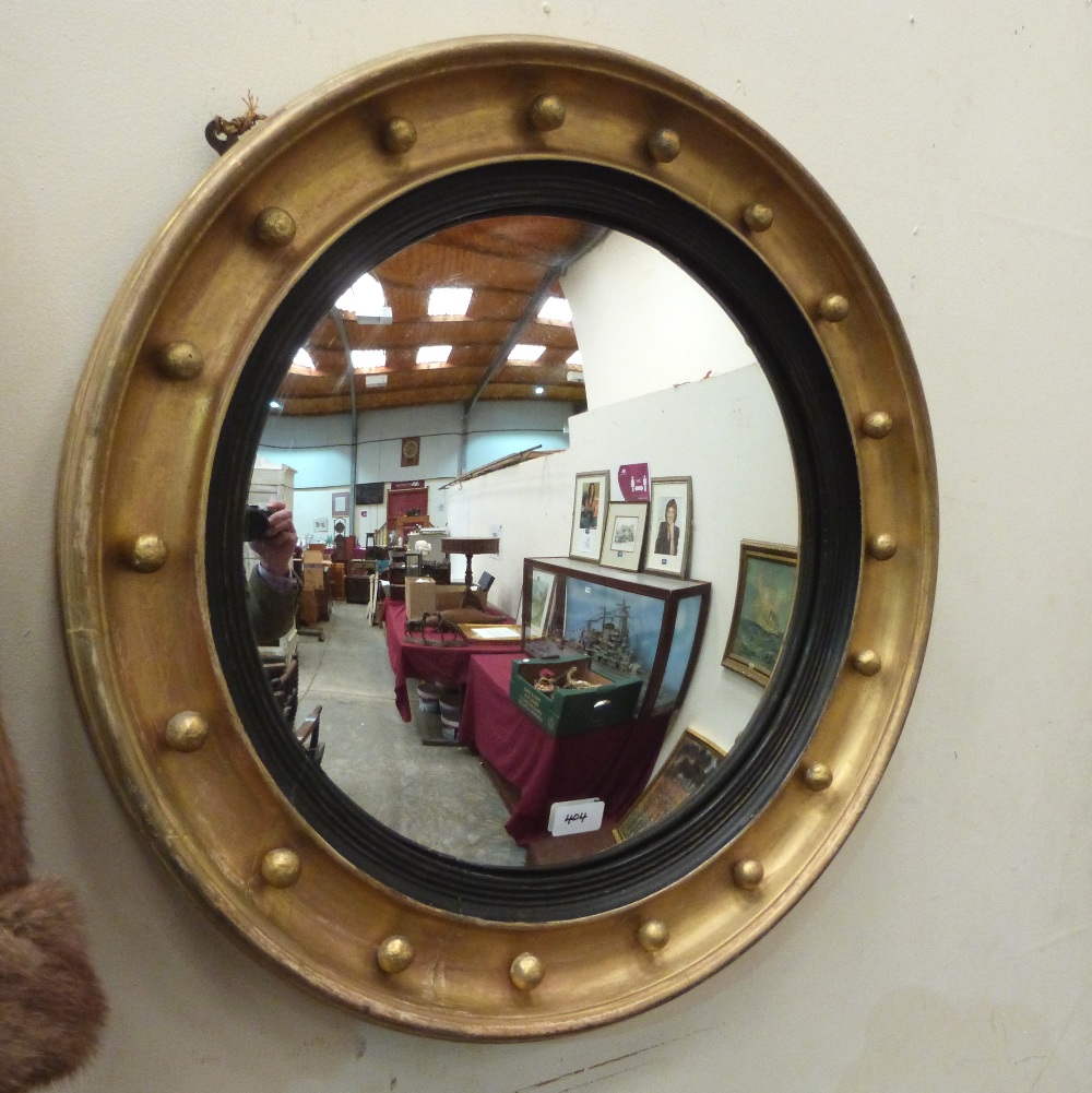 A 19th century giltwood convex looking glass with ebonised reeded slip. 25' diam