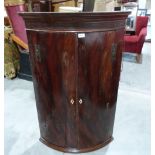 A George III mahogany bowfronted hanging corner cupboard. 44' high