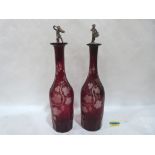 A pair of ruby glass decanters with figural stoppers with acid etched vine fruit decoration. 12'