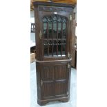 An oak standing corner cupboard enclosed by a glazed door with ecclesiastical style astragals. 74'