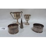 A small silver trophy cup; a silver eggcup, a pair of silver napkin rings and a silver snuffer.