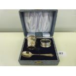 A silver three piece christening set comprising an eggcup, spoon and napkin ring. Various hallmarks.