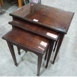 A nest of three mahogany occasional tables with inlet glass tops