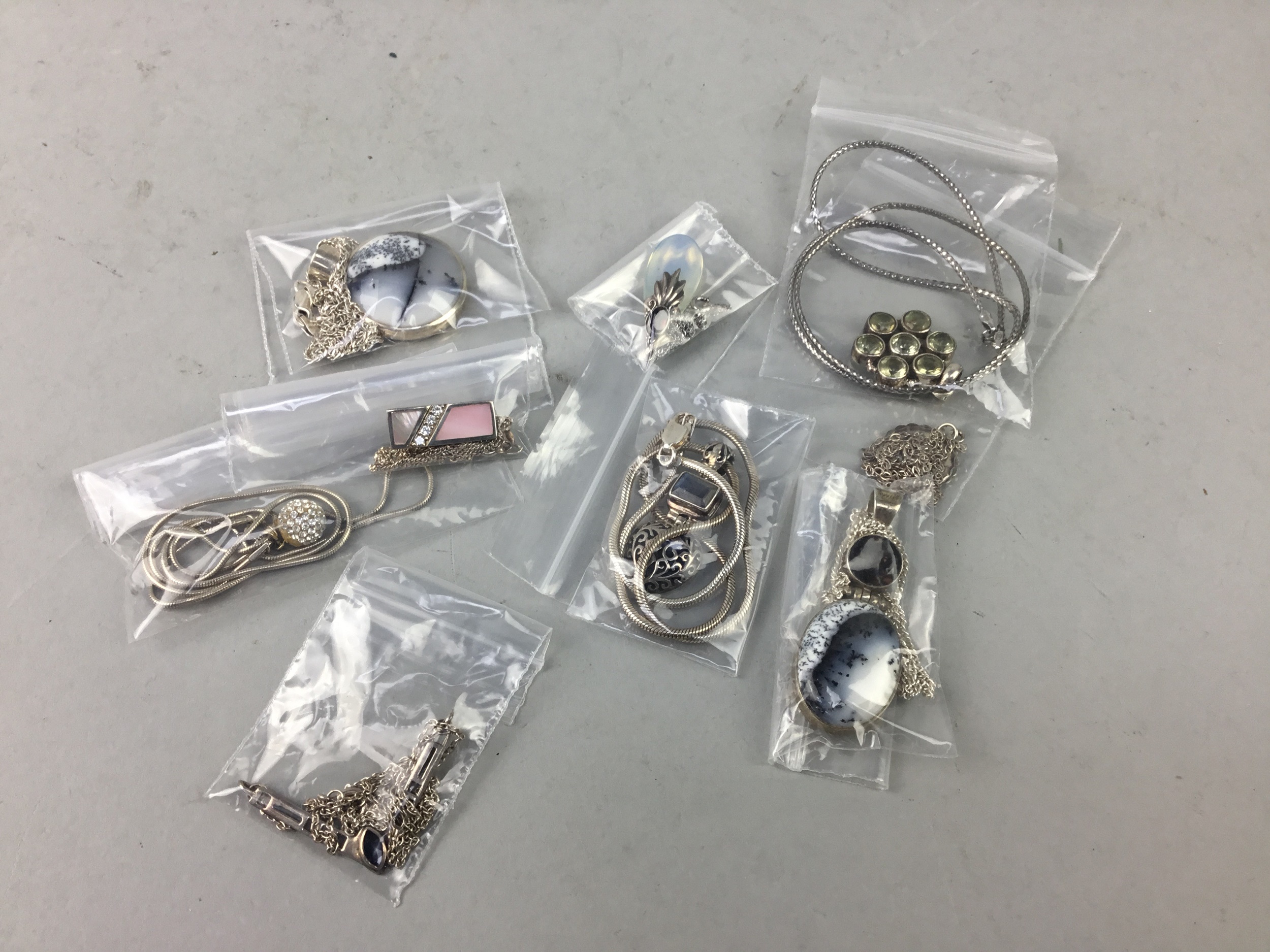 A COLLECTION OF NINE SILVER PENDANTS AND CHAINS