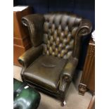 A BROWN LEATHER WING BACKED ARMCHAIR