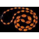 A NECKLACE OF AMBER COLOURED RESIN BEADS, WITH GLASS BEADS AT INTERVALS