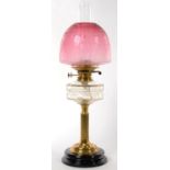 AN EDWARDIAN BRASS FLUTED COLUMNAR OIL LAMP WITH GLASS FOUNT, BRASS BURNER AND BLACK GLAZED