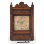 A CARVED OAK MANTEL TIMEPIECE WITH WINTERHALDER AND HOFFMEIER MOVEMENT, THE SQUARE BRASS DIAL WITH