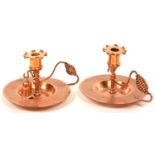 A PAIR OF ARTS AND CRAFTS COPPER CHAMBER STICKS WITH SPIRAL ROD HANDLE, NOZZLES, PAN 15.5CM D, C1910
