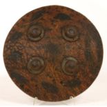 AN INDIAN LEATHER SHIELD, DHAL, WITH FOUR IRON BOSSES, 24.5CM D, PROBABLY 19TH C