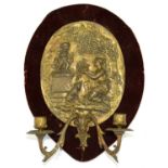 A GILT BRASS TWIN BRANCH WALL LIGHT, THE BACK PLATE IN THE FORM OF AN OVAL PLAQUETTE OF A WOMAN