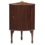 A GEORGE III BOW FRONTED MAHOGANY CORNER CUPBOARD, C1800  with brass handle to the top and tambour