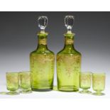 A PAIR OF FRENCH GILT LIME GREEN GLASS DECANTERS AND STOPPERS AND FOUR MINIATURE FOOTED BEAKERS EN