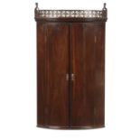 A GEORGE III BOW FRONTED MAHOGANY CORNER CUPBOARD, C1780  the fretwork frieze with thistle