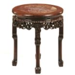 A CHINESE CARVED HONGMU STAND, C1900 with stone inset top, 48cm h; 42cm diam Good condition with