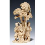 A JAPANESE IVORY OKIMONO OF A WOODCUTTER AND TWO FIGURES WITH A TETHERED MONKEY ABOVE IN THE CROWN