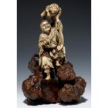 A JAPANESE STAINED IVORY OKIMONO OF GAMMA SENNIN, ON CONTEMPORARY CARVED ROOT WOOD STAND, 24CM H,