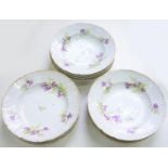 A SET OF TWELVE LIMOGES EARTHENWARE DESSERT PLATES PAINTED WITH FLOWERS, EARLY 20TH C