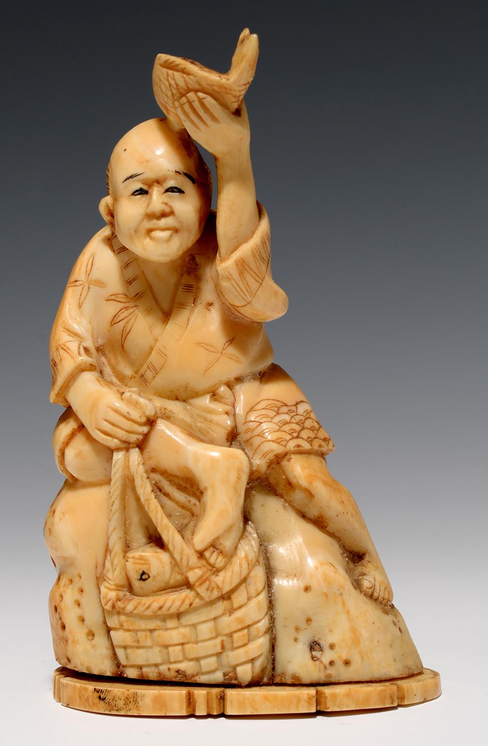 A JAPANESE IVORY OKIMONO OF A FISHERMAN SEATED ON A ROCK, 10.5CM H, SIGNED, MEIJI PERIOD