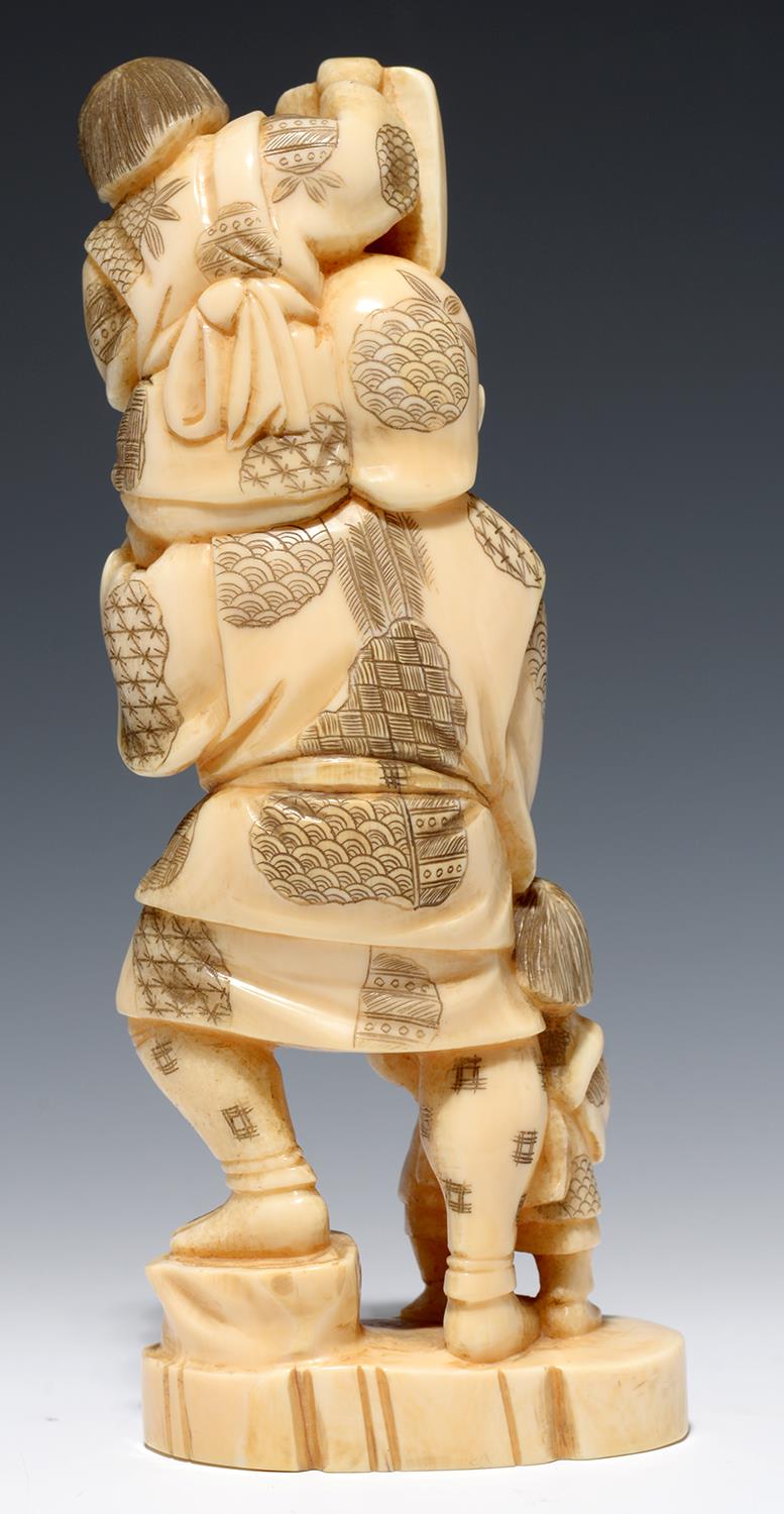 A JAPANESE IVORY OKIMONO OF A MASK SELLER AND TWO CHILDREN, 17CM H, SIGNED, MEIJI PERIOD - Image 2 of 2