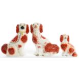 THREE STAFFORDSHIRE EARTHENWARE MODELS OF SPANIELS, WITH SPONGED RUST FEATHERY MARKS, 28CM H, 19TH C