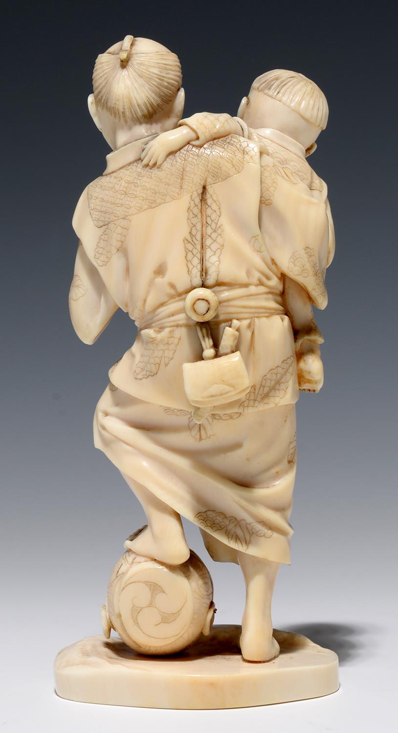 A JAPANESE IVORY OKIMONO OF A STREET VENDOR AND HIS SMALL SON, THE MAN'S FOOT RESTING ON A - Image 2 of 2