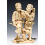 A JAPANESE IVORY OKIMONO OF TWO WOODCUTTERS, EACH HOLDING A PIPE, 15CM H, SIGNED, MEIJI PERIOD