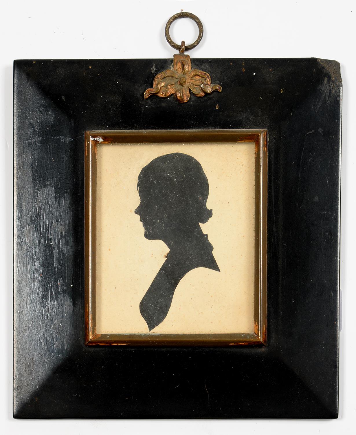 A CUT PAPER SILHOUETTE OF A YOUNG WOMAN, PAPIER MACHE FRAME WITH BRASS HANGER, 16 X 15CM OVERALL