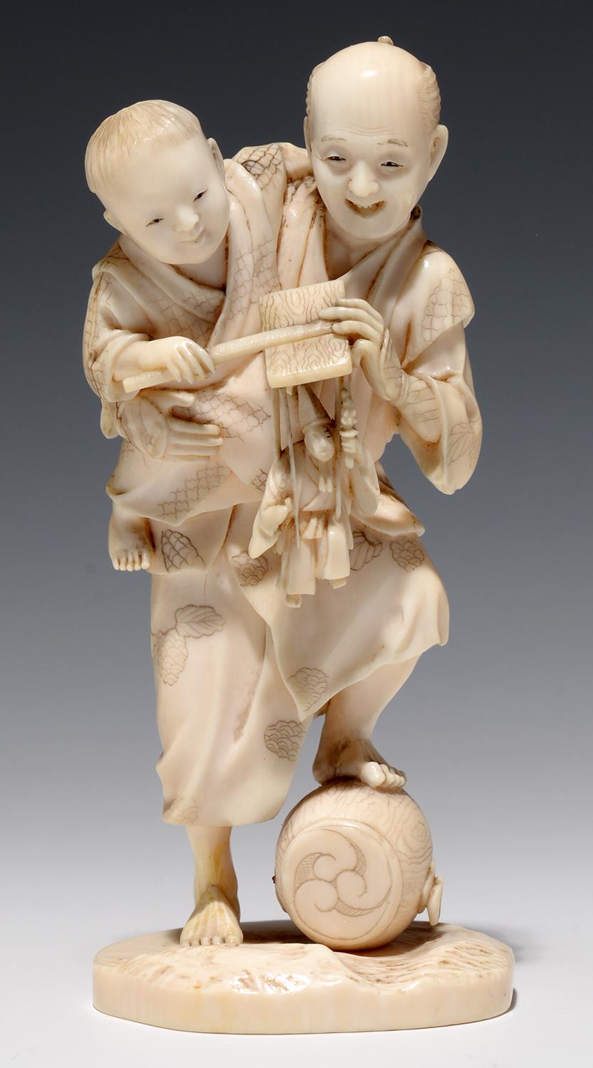 A JAPANESE IVORY OKIMONO OF A STREET VENDOR AND HIS SMALL SON, THE MAN'S FOOT RESTING ON A