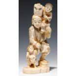 A JAPANESE IVORY OKIMONO OF A MASK SELLER AND TWO CHILDREN, 17CM H, SIGNED, MEIJI PERIOD