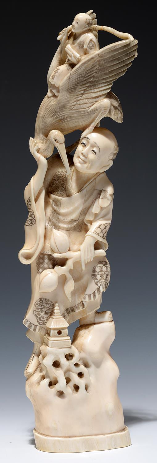 A JAPANESE IVORY OKIMONO OF A MAN HOLDING A PEACH AND VISITED BY  JUROJIN CARRIED ON A  A STORK ON