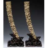 A PAIR OF CHINESE PIERCED IVORY TUSK CARVINGS ON CONTEMPORARY OPENWORK HARDWOOD STANDS, CARVED AS