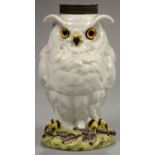 A FRENCH PORCELAIN OWL NOVELTY OIL LAMP BASE WITH VIVID YELLOW AND BLACK EYES, PERCHED ON A GREEN