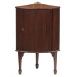 A GEORGE III BOW FRONTED MAHOGANY CORNER CUPBOARD, C1800, WITH BRASS HANDLE TO THE TOP AND TAMBOUR